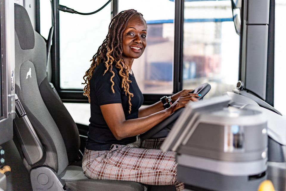 Die kenianische Busfahrerin Millicent Awiti sitzt hinter dem Steuer eines Linienbusses im Betriebshof in Flensburg