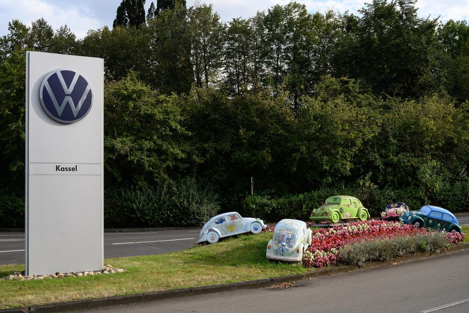 Blick auf eine Stele mit dem Logo von VW und dem Schriftzug Kassel vor dem Werksgebäude.