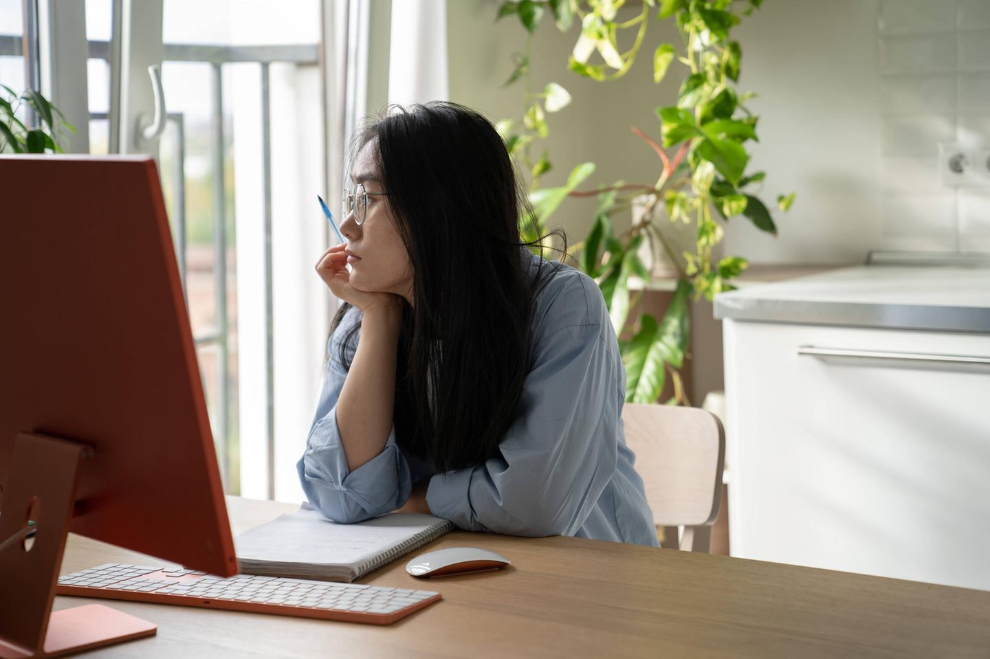 Junge Frau sitzt grübelnd im Homeoffice
