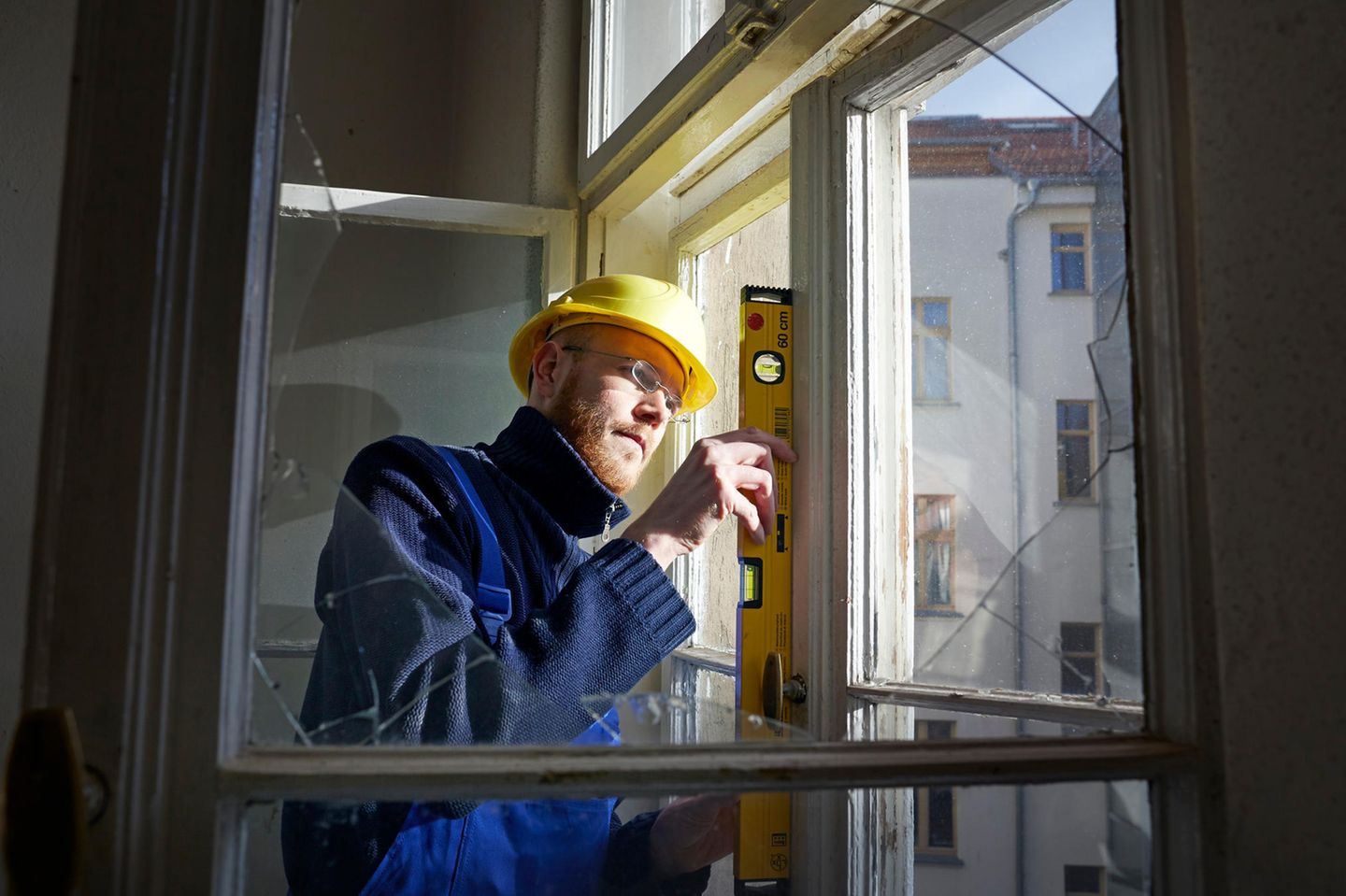 When the Bau gift is given, it is a dream "Engpassberufe": Here you see a Bauerbeiter with gelbem Helm prüft with Wasserwaage and Fenster