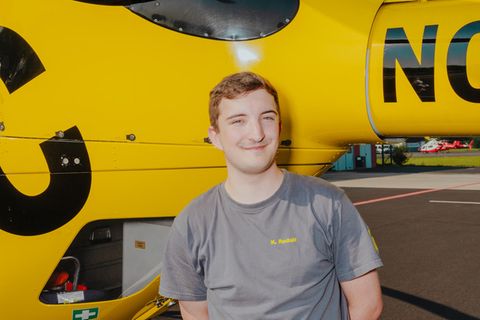 Azubi Kai Rudolf vor einem ADAC-Rettungshubschrauber