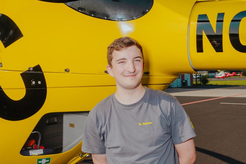 Azubi Kai Rudolf vor einem ADAC-Rettungshubschrauber