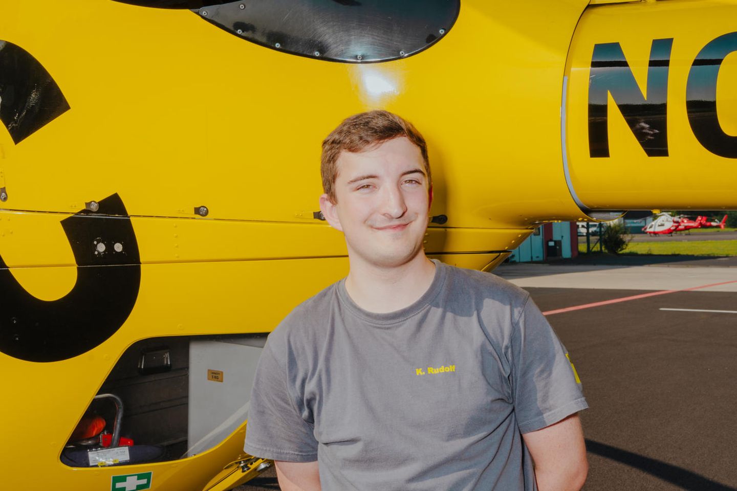 Azubi Kai Rudolf vor einem ADAC-Rettungshubschrauber