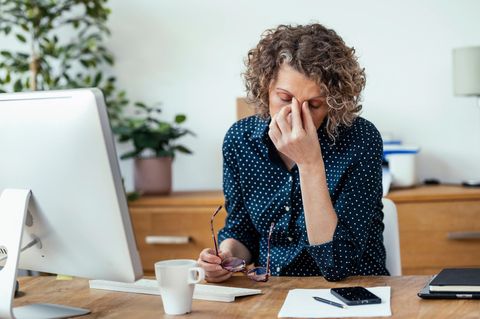 Frau sitzt erschöpft am Schreibtisch