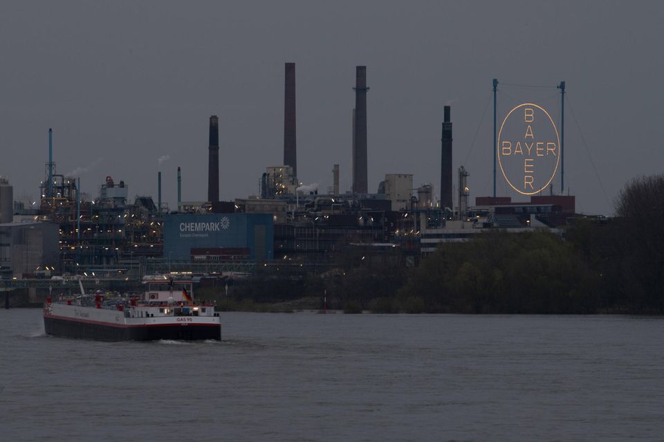 Ein Frachtschiff passiert in der Dämmerung den Chempark in Leverkusen