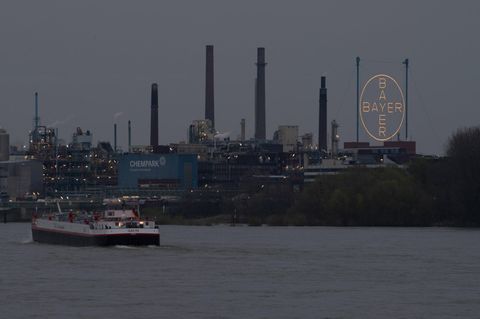 Ein Frachtschiff passiert in der Dämmerung den Chempark in Leverkusen