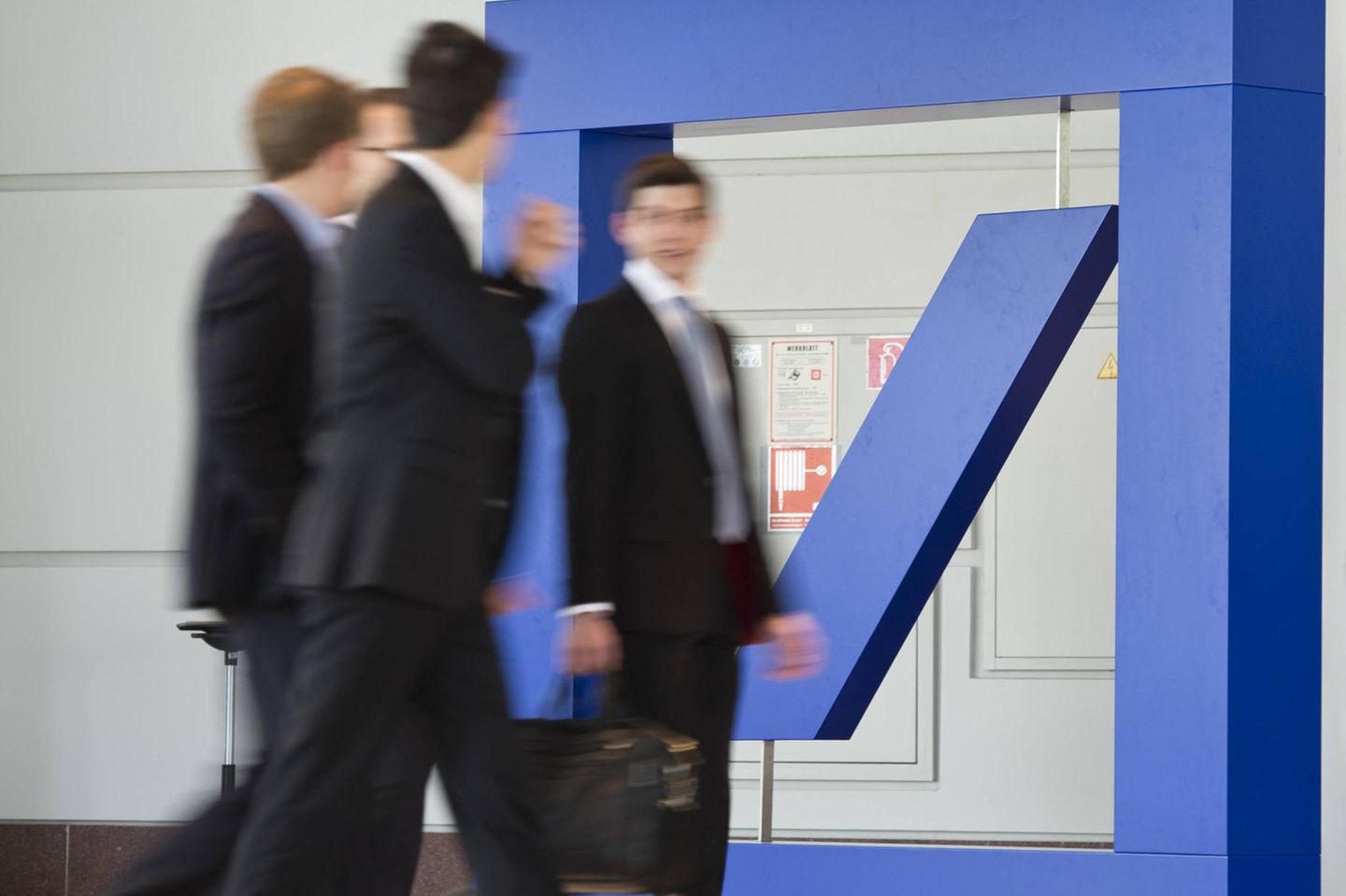 Männer laufen an einem großen Logo der Deutschen Bank vorbei