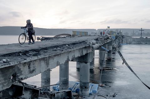 Anwohner überqueren im Januar 2023 eine zerstörte Brücke über den Fluss Siwerskyj Donez in der Region Charkiw