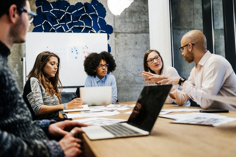 Frauen und Männer sitzen an einem Tisch und diskutieren
