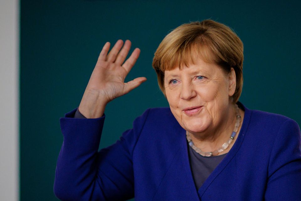 Angela Merkel, eine Frau mit kurzen Haaren, Kette und Blazer, schaut zufrieden