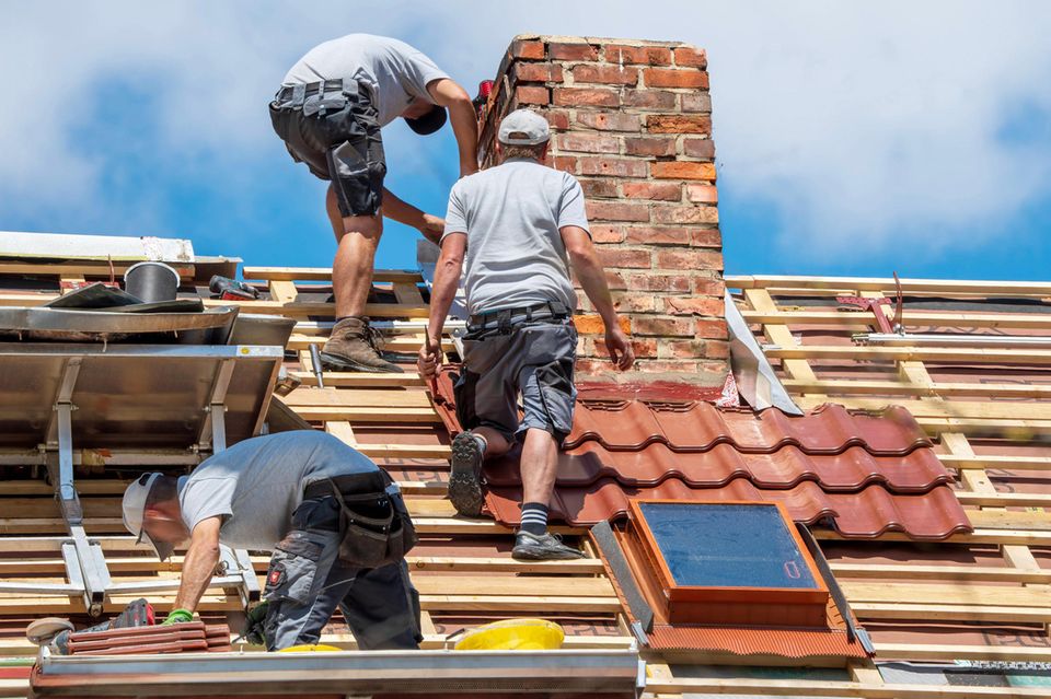 Dachdecker bei der Arbeit: KfW-Förderung gibt es für den Kauf einer sanierungsbedüftigen Immobilie