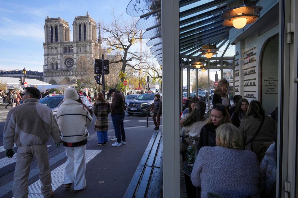 Menschen im Café in Paris mit Blick auf die Kathedrale Notre Dame