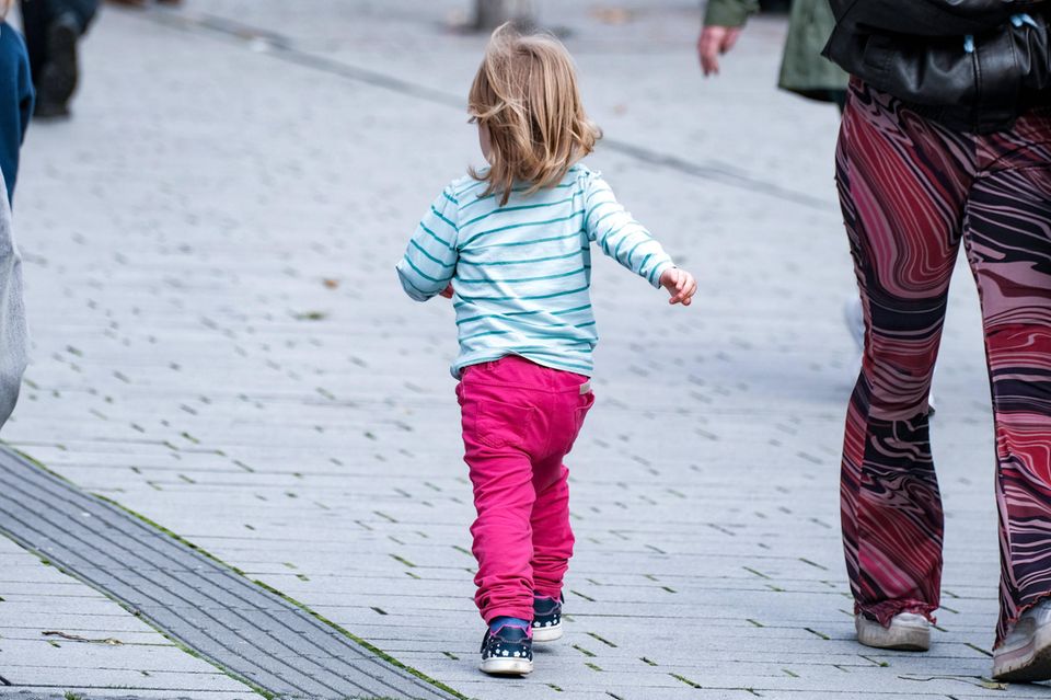 Ein kleines Mädchen geht auf einem Gehweg
