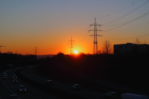 Drei Strommasten vor der untergehenden Sonne