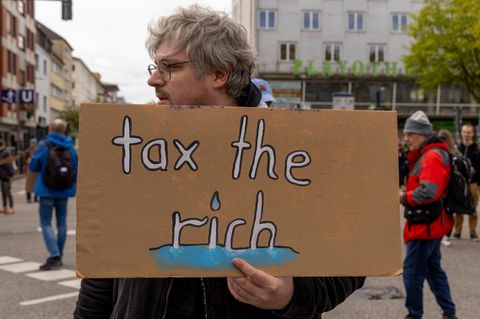 Mann mit Plakat „Tax the rich“