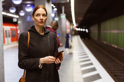 Berufspendlerin wartet im S-Bahnhof in Frankfurter auf ihren Zug und denkt nach: über das Gehalt?