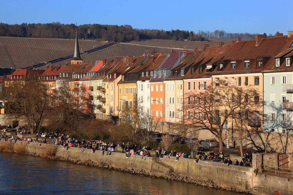 Menschen sitzen entlang der Altstadthäuser am Main, Würzburg