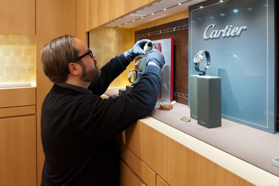 Mitarbeiter richtet Uhren von Cartier in einer Ladenvitrine