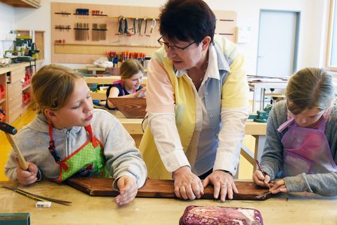 Kinder mit Lehrerin während eines Werkunterrichtes in einer Schule