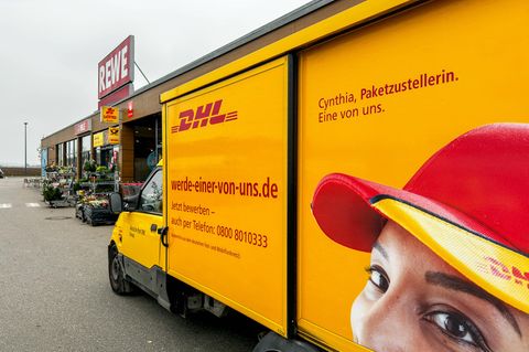 DHL Deutsche Post Zustellfahrzeug mit Mitarbeiter-Werbung vor einem REWE-Markt