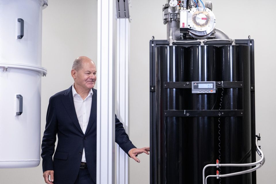 Olaf Scholz steht neben einem Quantencomputer