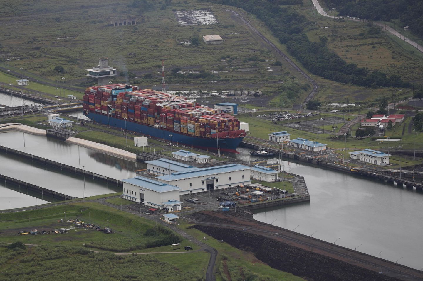 Ein Frachtschiff voller Container steuert durch eine sehr enge Stelle des Panamakanals.