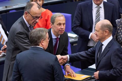 Friedrich Merz (l.) gibt Olaf Scholz im Bundestag die Hand