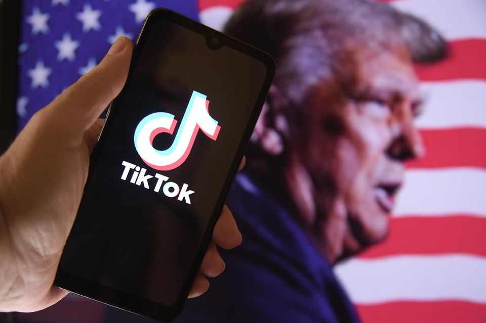 Smartphone mit geöffneter Tiktok-App vor Foto von Donald Trump