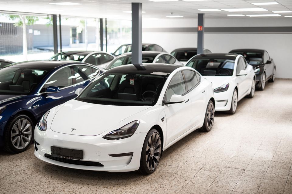In einem lichtdurchfluteten Ausstellungsraum stehen mehrere auf Hochglanz polierte Teslas