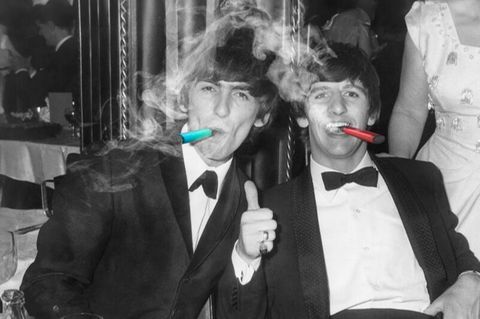1964: Die britischen Musiker George Harrison und Ringo Starr, Mitglieder der Rockgruppe The Beatles, rauchen Zigarren