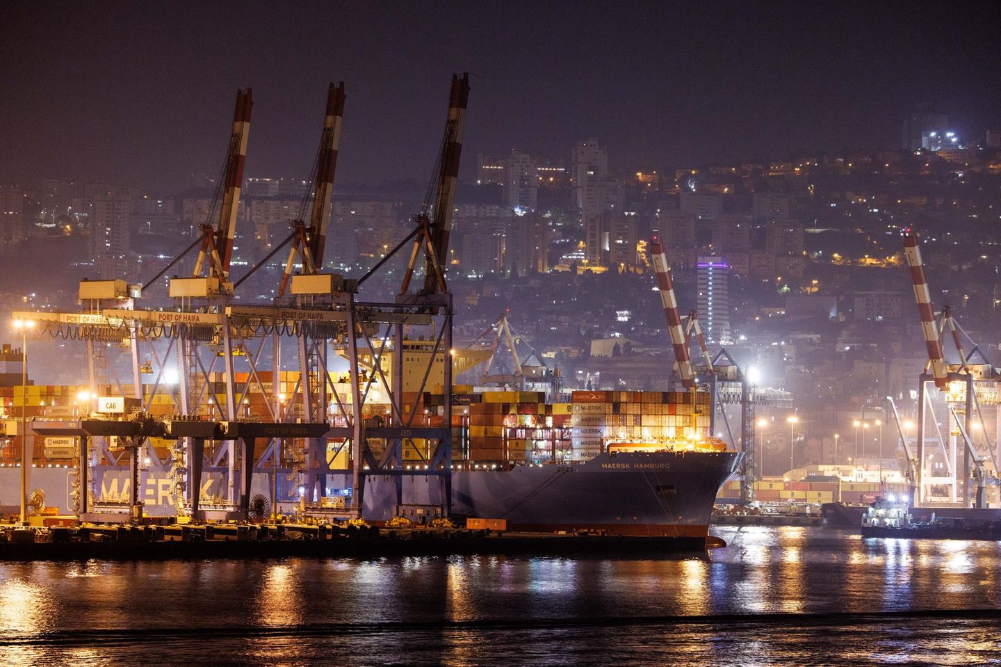 Ein Containerschiff liegt in der Dunkelheit im Hafen