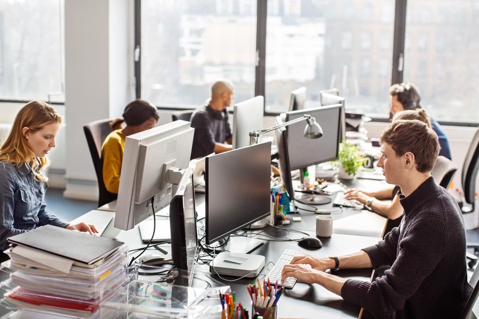 Junge Mitarbeiterinnen und Mitarbeiter arbeiten im Büro an ihren Computern