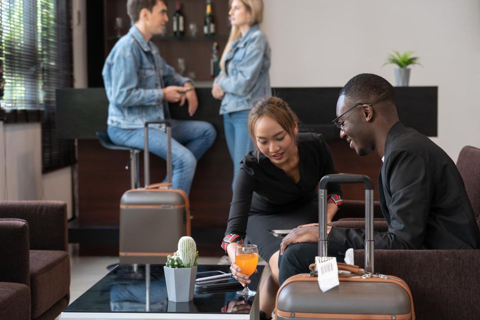 Geschäftsmann in Flughafen Terminal Lounge, Kellnerin serviert Orangensaft