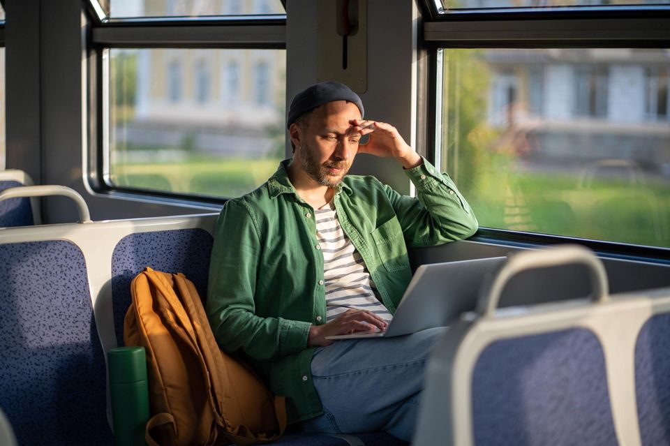 Ein Mann im Zug mit Laptop auf dem Schoß
