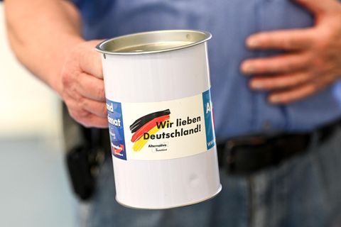 Jemand hält eine Spendenbüchse der AfD, auf der "Wir lieben Deutschland!" steht