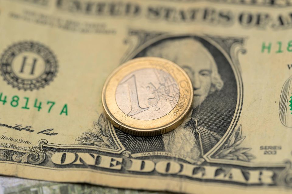Eine 1-Euro-Münze liegt auf einem 1-Dollar-Schein