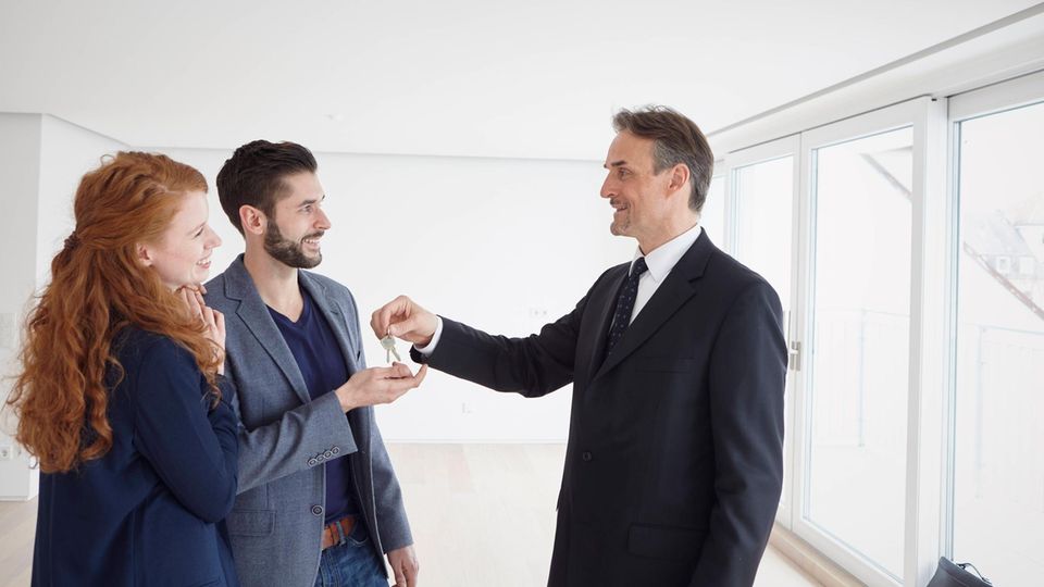 Immobilienmakler übergibt Schlüssel an Paar