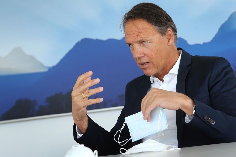 Achim Theiler spricht in einem Interview und hat einen Mundschutz in der Hand
