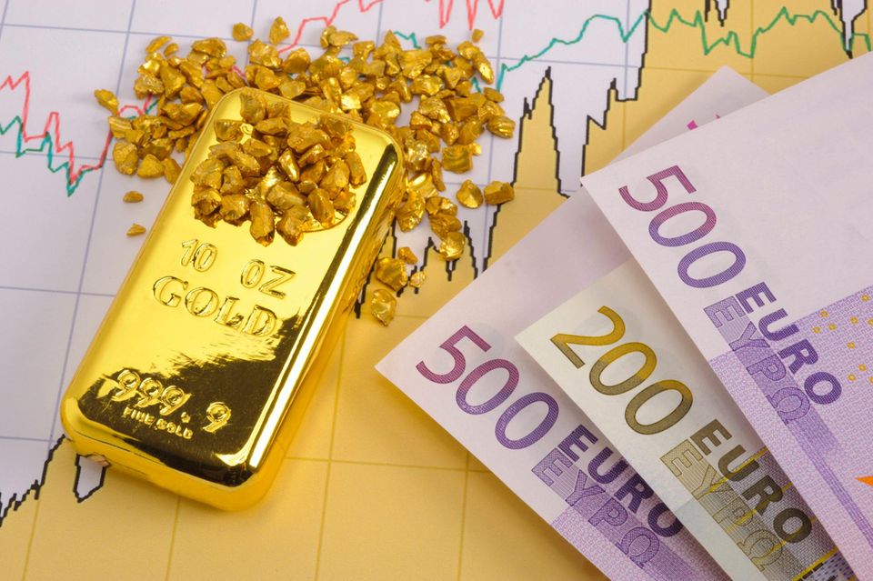 Auf dem Chart einer Börse liegen ein Goldbarren, Goldnuggets und Geldscheine