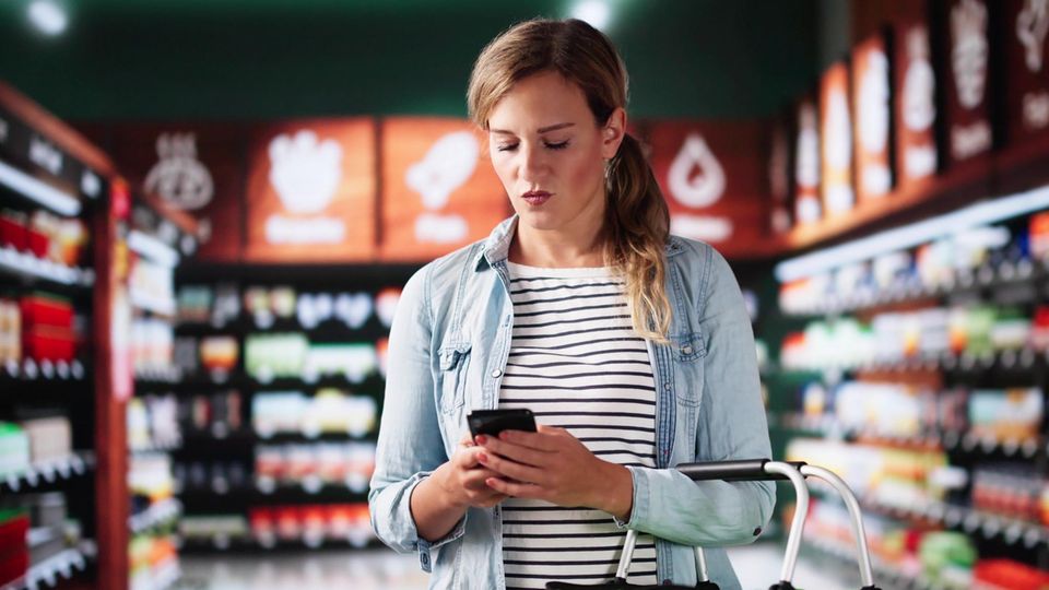 Kundin mit Handy im Supermarkt Kundin mit Handy im Supermarkt