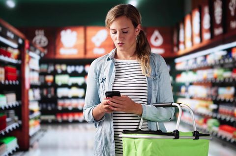 Kundin mit Handy im Supermarkt