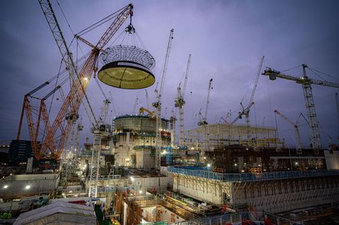 Ingenieure setzen den größten Kran der Welt ein, um eine 245 Tonnen schwere Stahlkuppel auf das erste Reaktorgebäude zu heben