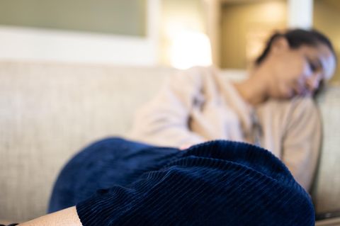 Eine Frau liegt erschöpft auf einem Sofa