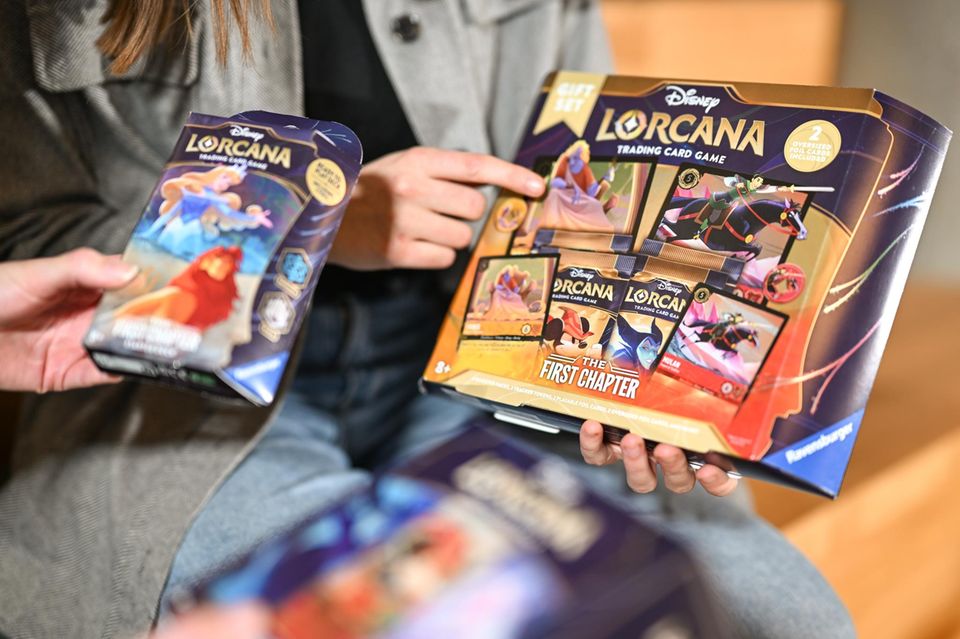Zwei Mitarbeiterinnen des Spieleherstellers Ravensburger AG halten das neue Sammelkartenspiel in den Händen