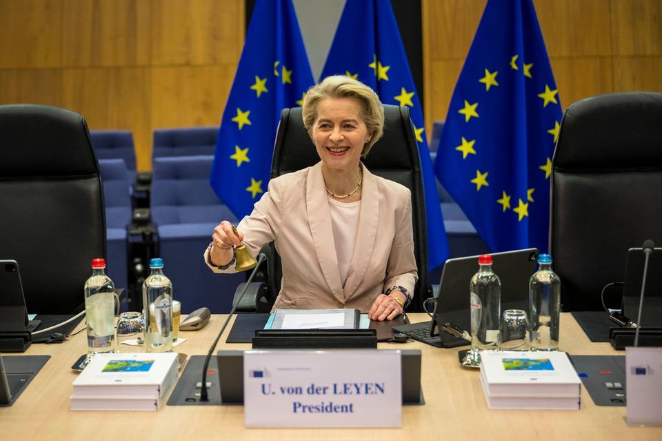 EU-Kommissionspräsidentin Ursula von der Leyen sitzt an einem Tisch vor EU-Flaggen und klingelt eine Klocke