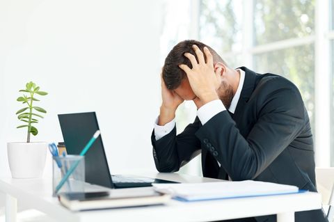 Gestresster Geschäftsmann sitzt am Schreibtisch