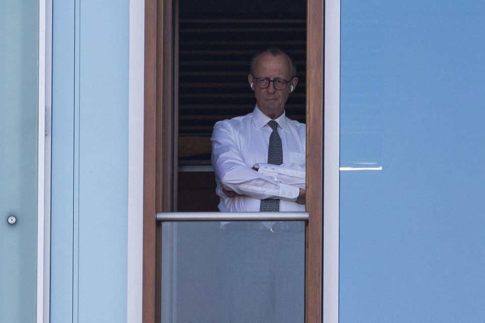 Friedrich Merz steht mit verschränkten Armen an einem Fenster