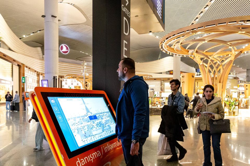 Ein Mann steht vor einem Bildschirm im Flughafen von Istanbul