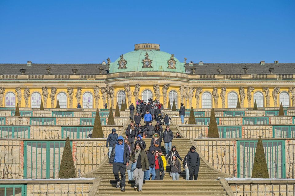 Besucher kommen die Treppen von Schloss Sanssouci in Potsdam herunter
