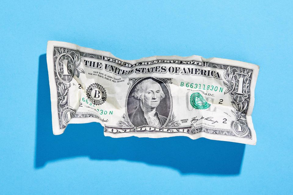 Zernknitterter Dollar-Schein vor blauem Hintergrund
